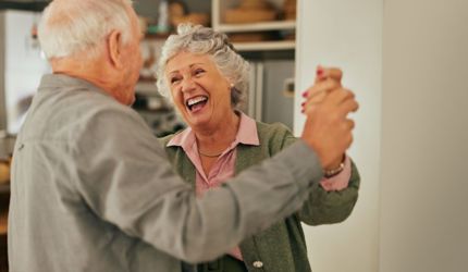 Supporting a Loved One at Home with Dementia article_Seniors dancing in their home blissfully happy