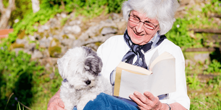 Elderly woman reading and petting her dog