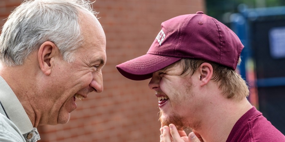 Disability client with maroon cap and shirt smiling