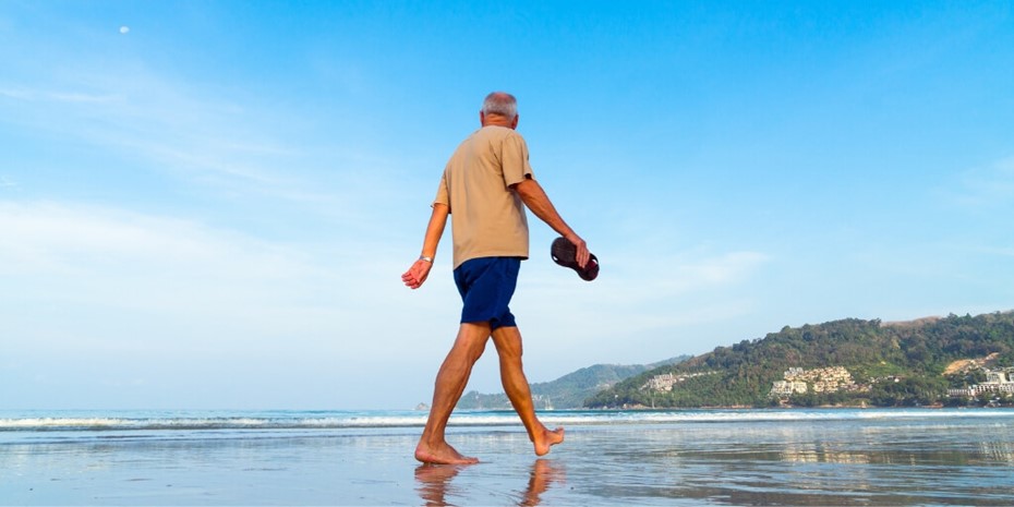 Elderly man walking on beach