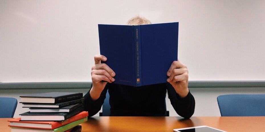 Man reading a book with a plain blue cover