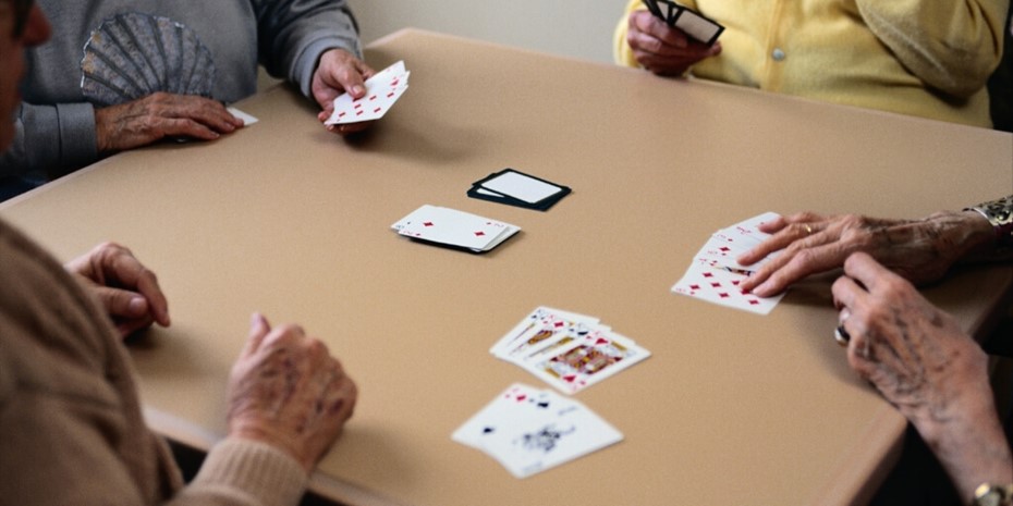 Close up of elderly peoples hands playing cards on a table