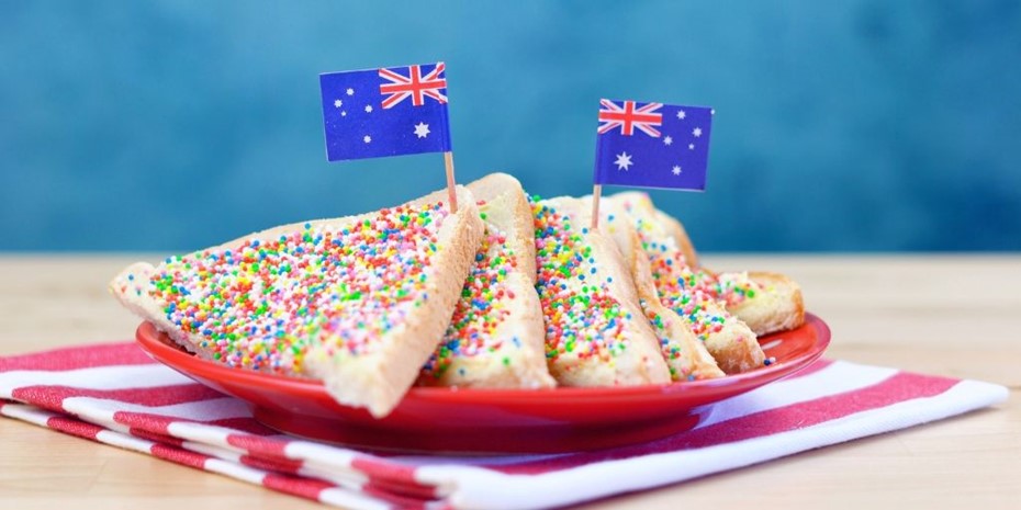 Six slices of fairy bread with two small Australian flags on a red plate and napkin