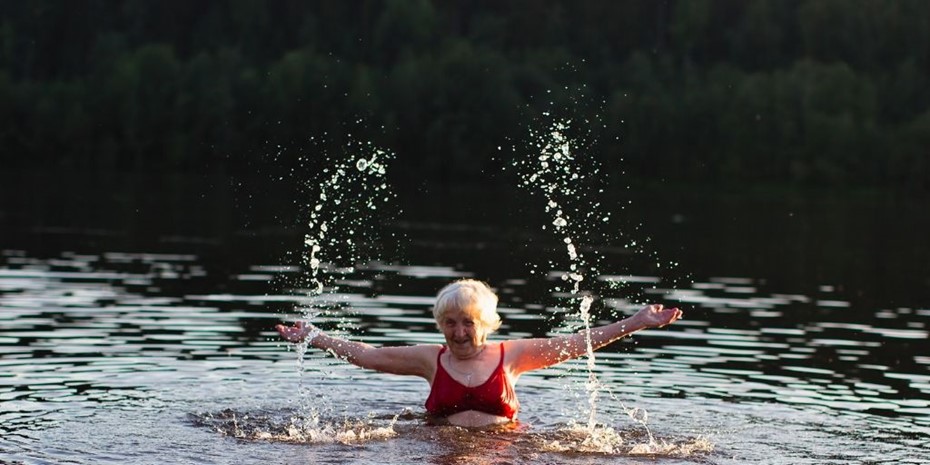 Elderly woman wearing red bathing top splashing in water