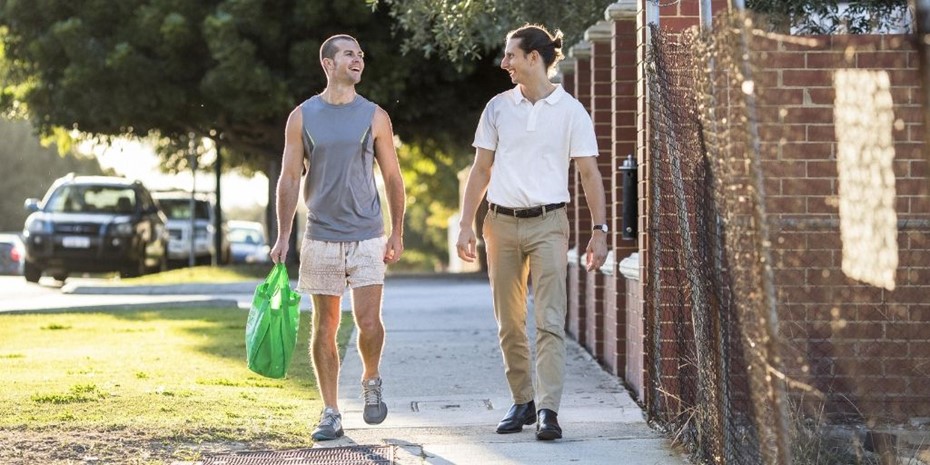 Two men walking and carrying groceries