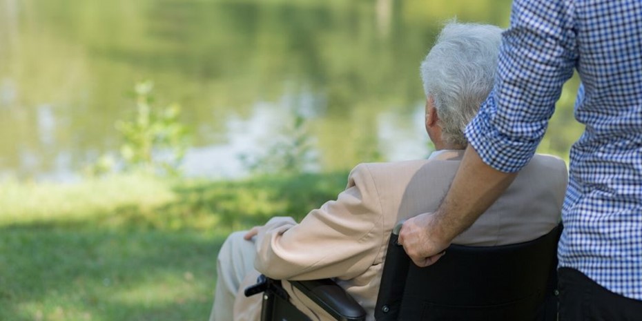 Elderly man in wheelchair looking out at a lake