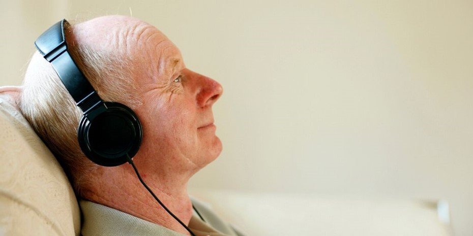 Profile photo of elderly man listening to music with headphones smiling