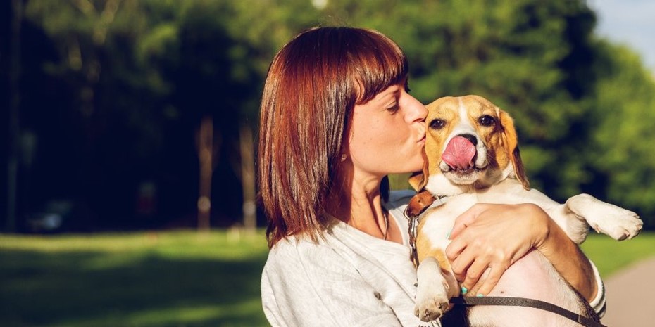 Woman with brown hair holding and kissing a dog