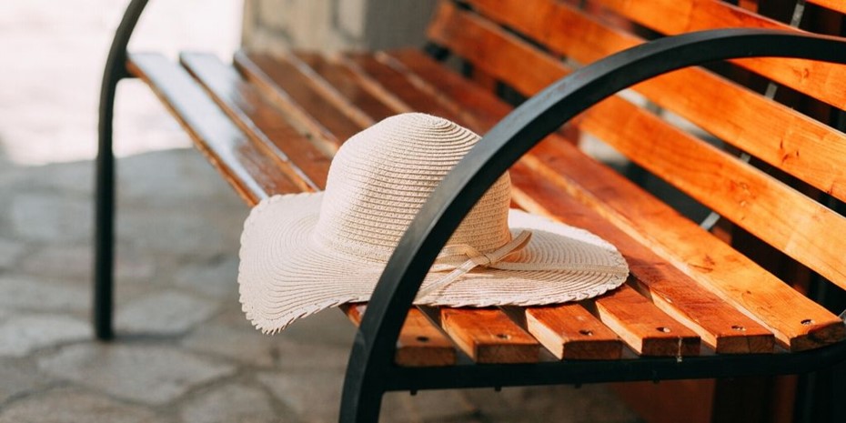A wide brimmed hat sitting on a bench outside