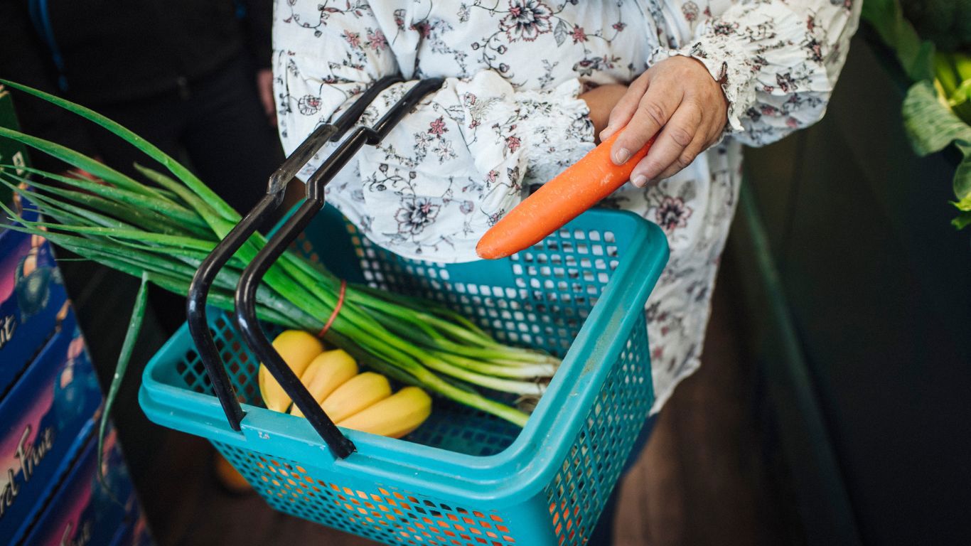 Brightwater Dietitian Services_woman with shopping basket full of fresh colourful vegetables such as carrots, bananas and spring onion