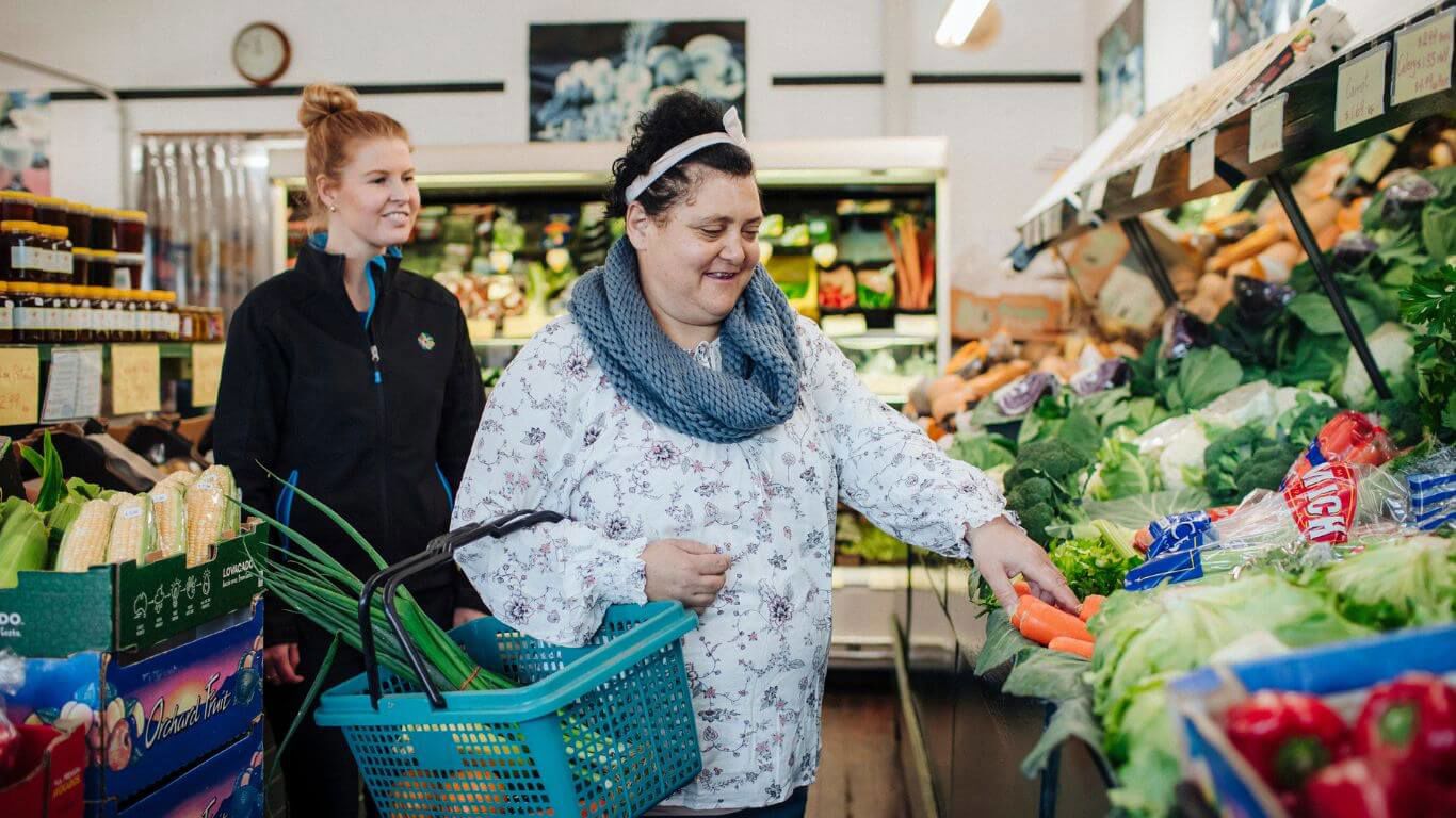 Brightwater Dietitian Services_support worker taking disability client out shopping for groceries at the local supermarket to pick fresh veggies