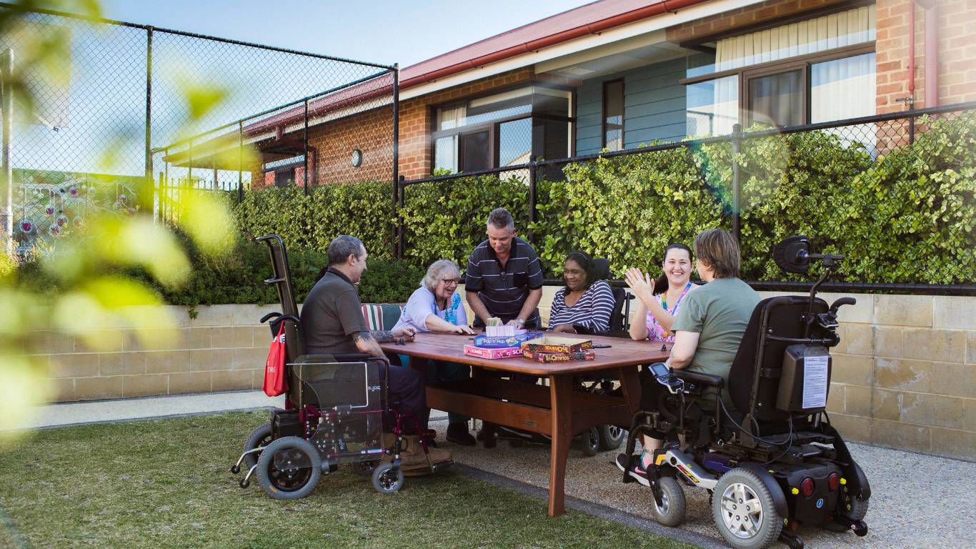 Brightwater Oats Street_disability clients sitting around a table outdoors playing games together