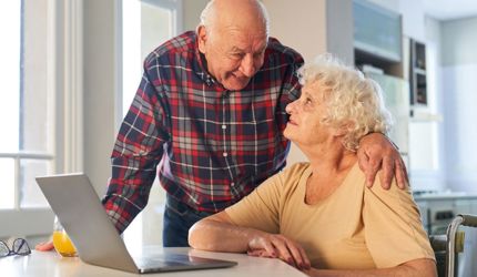 Support at Home_seniros looking at laptop reading online guides and handbook together