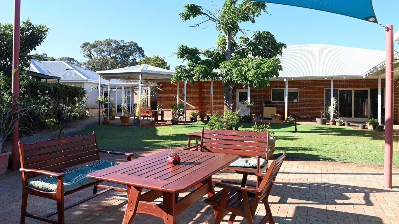 Brightwater Marangaroo Transitional Accommodation Program_outdoor area with sun shade, wooden table and chairs, lush greenery, garden and grass