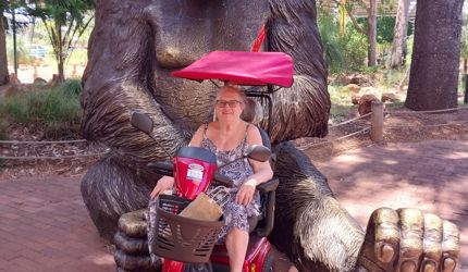 Home care client Susan visits Perth Zoo thanks to Life's Possibilities_in front of giant gorilla statue in her scooter