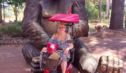 Home care client Susan visits Perth Zoo thanks to Life's Possibilities_in front of giant gorilla statue in her scooter