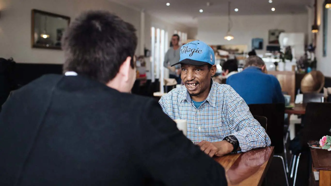 Brightwater Psychology Services_disability client chatting with support worker in cafe about his rehab goals